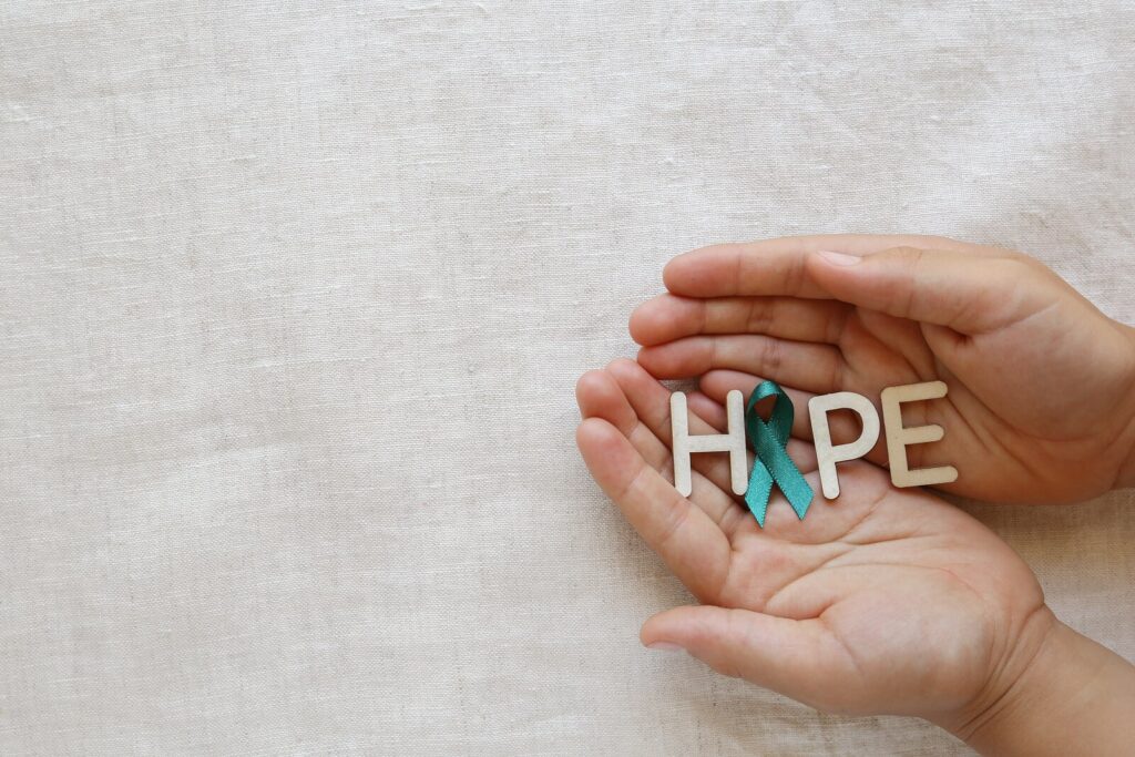 teal awareness ribbon in hands with the word hope