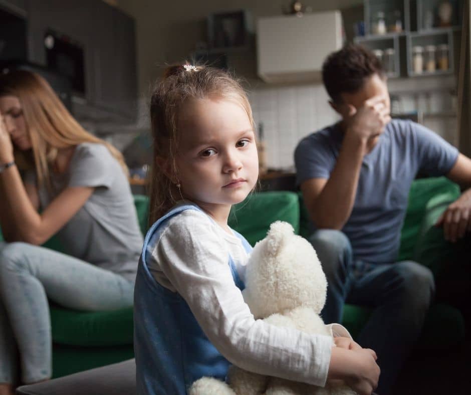 frustrated looking parents with small child looking back sadly